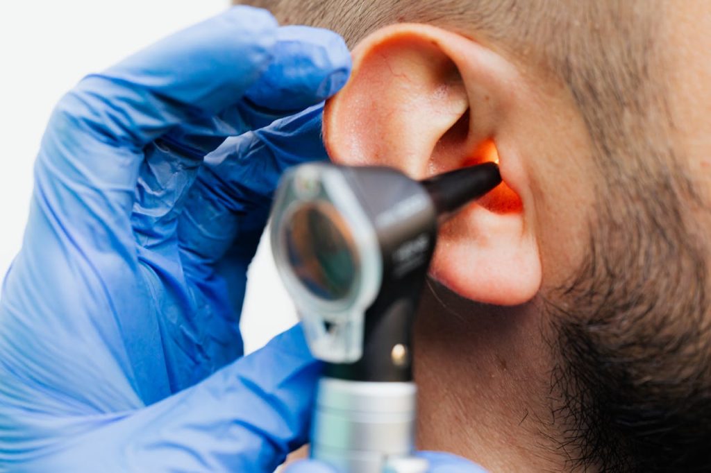Close-up of a doctor using an otoscope to examine a patients ear in a clinical setting.